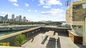 A rooftop terrace with a view of the Sydney Opera House and Harbour Bridge, featuring outdoor seating and a water view. - Heart Of The City Minutes From Macleay Street (Potts Point)