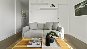 A living room with a grey sofa, a coffee table with a book and a black vase, and a bonsai tree. - Modern Potts Point Studio (Potts Point)