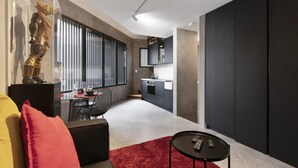 Un salon moderne avec un canapé, un tapis rouge et un coin repas comprenant une table et des chaises.