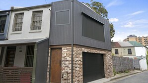 Un bâtiment à deux étages doté d’une porte de garage, d’une façade en briques et d’une grande fenêtre à l’étage supérieur.