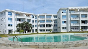 A modern building with a swimming pool, surrounded by a well-maintained lawn and a stone pathway. - Inviting 1-bed Apartment in Malindi (Malindi)