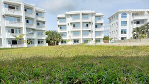 A multi-story residential building with balconies, a grassy lawn, and palm trees. - Inviting 1-bed Apartment in Malindi (Malindi)