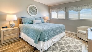 Una camera da letto con un letto, due comodini, una sveglia a parete, un elemento decorativo, tende di pizzo e un tappeto a motivi.
