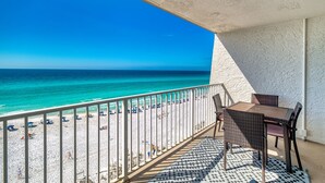 Un balcone con vista sulla spiaggia e sull'oceano, un tavolo e sedie.
