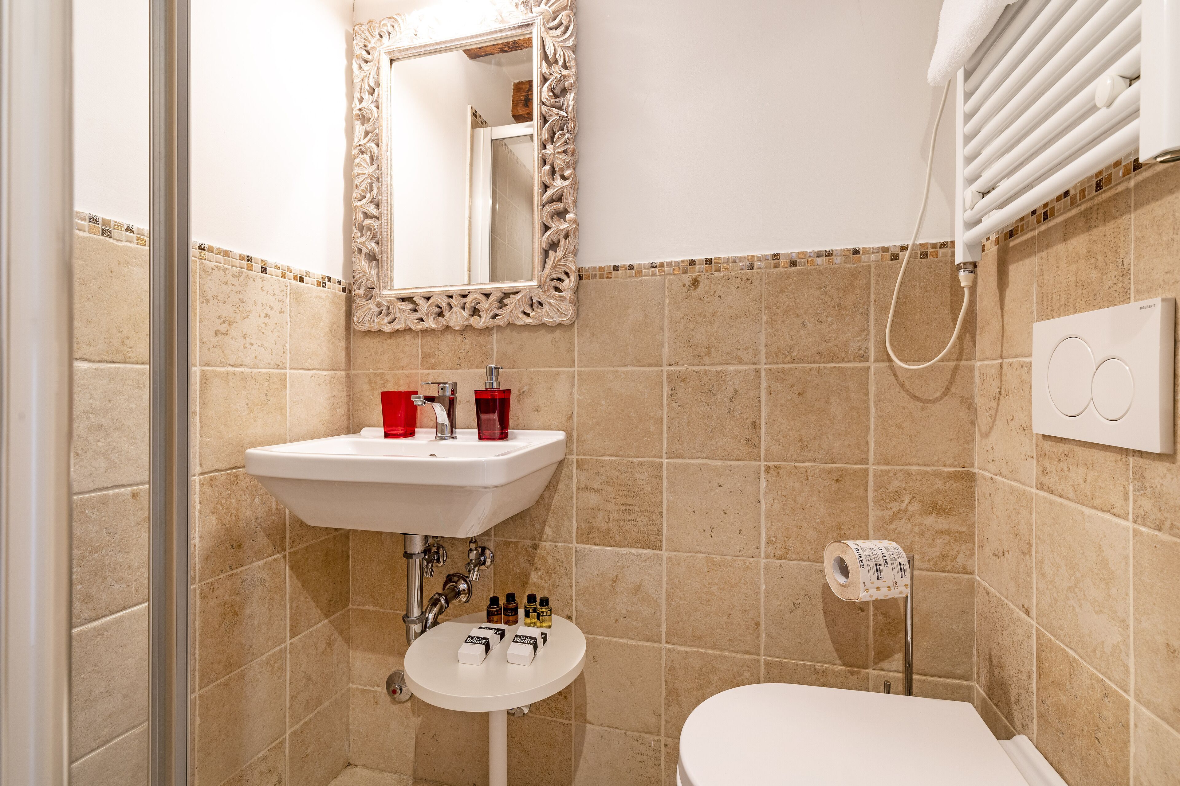 A bathroom with a white sink, a mirror with an ornate frame, and a shower area.