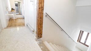 Un escalier avec une poutre en bois, une main courante et un mur blanc.