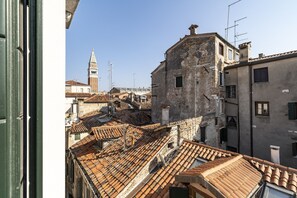 Vista de un paisaje urbano con tejados de terracota, una imponente torre del reloj y una mezcla de edificios antiguos y modernos.