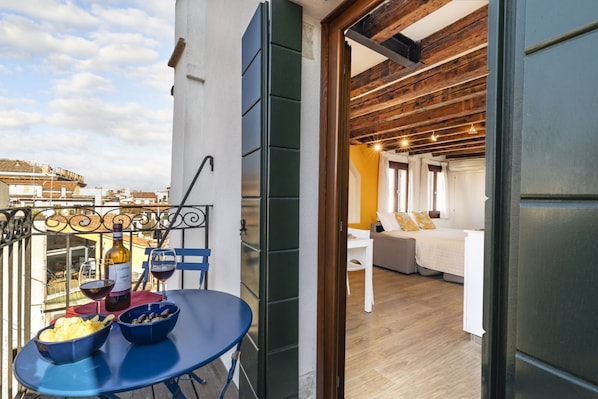 A balcony with a table set for two, wine glasses, and a bottle of wine.