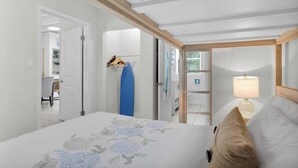 Une chambre à coucher avec un lit, une lampe de chevet, un porte-vêtements suspendu et une vue sur la salle de bain.