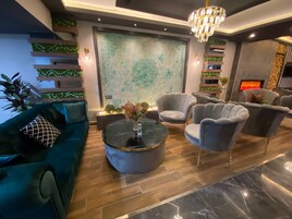Una sala de estar moderna con un sofá verde, sillones grises, una mesa de centro redonda y una chimenea.