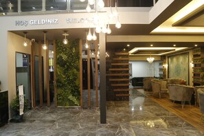 A modern lobby with a marble floor, a reception desk, and a seating area with plush chairs. - Grand Zara Otel (Kayseri)