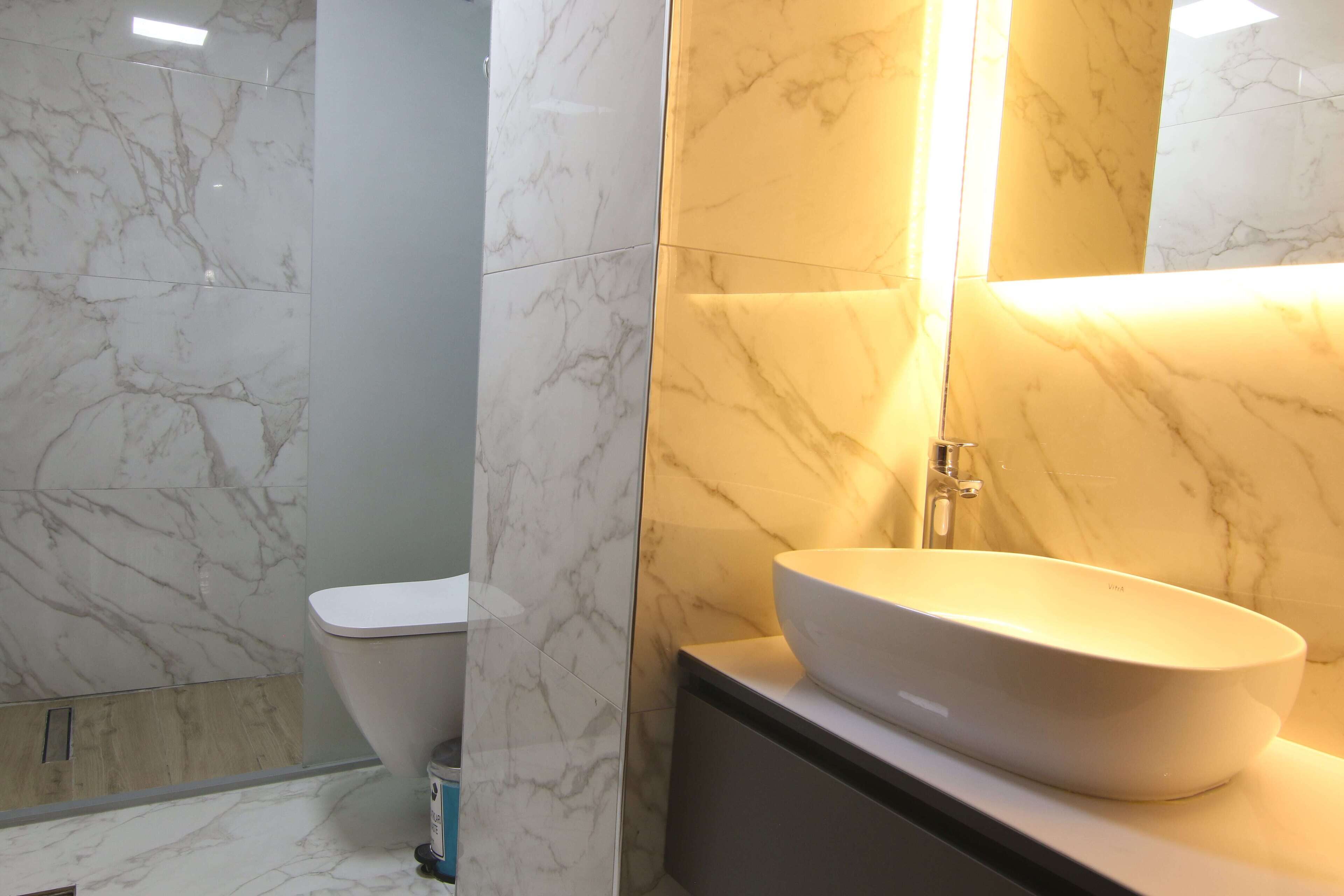 A bathroom with a white toilet, a sink with a bowl, and marble walls.