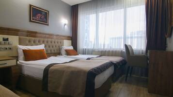 Habitación de hotel con dos camas, un escritorio y una silla.