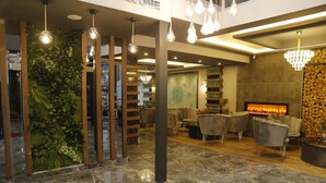 A modern lobby with a fireplace, seating area, and a green wall with plants. - Grand Zara Otel (Kayseri)