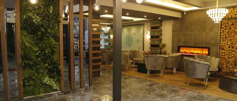 Un lobby moderno con chimenea, zona de estar y pared verde con plantas.