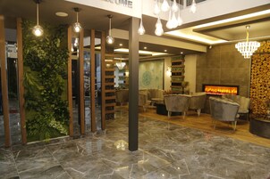A modern lobby with a fireplace, seating area, and a green wall with plants.