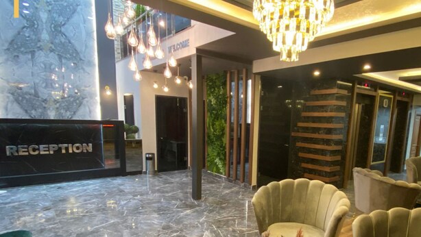 A reception area with a marble floor, a chandelier, and a reception desk labeled "RECEPTION". - Grand Zara Otel (Kayseri)