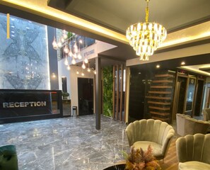 Uma área de recepção com piso de mármore, um candelabro e um balcão de atendimento identificado como "RECEPTION".