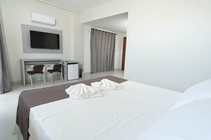 Habitación de hotel con cama, escritorio, dos sillas, televisor y cortina de ducha.