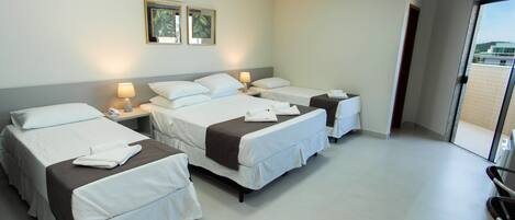 Een hotelkamer met drie bedden, een kleine tafel en een stoel.