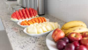 Eine Küchenarbeitsplatte mit verschiedenen Früchten, darunter Wassermelone, Orangen, Bananen, Äpfel und Pflaumen.