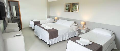 A hotel room with four beds, a desk, and a mirror.