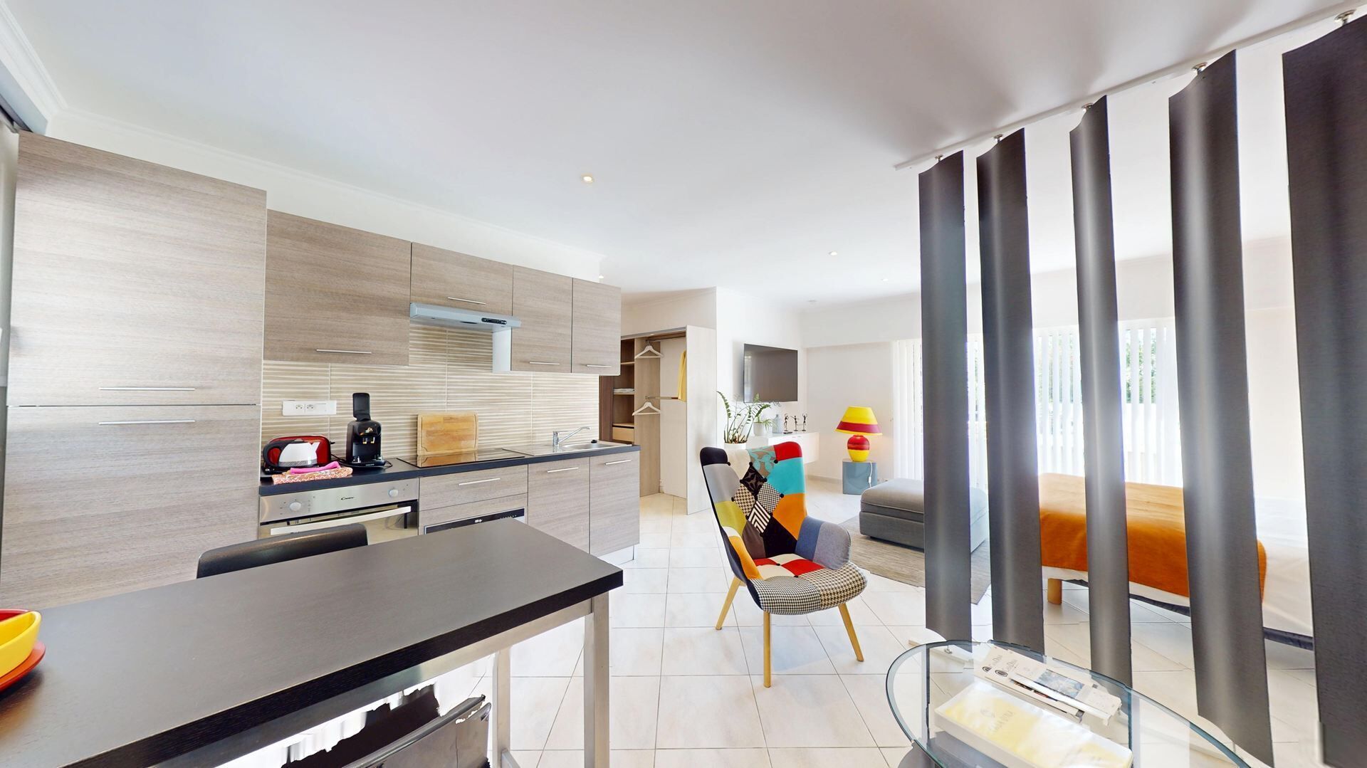 A modern kitchen with a dining area, a sofa, and a TV.