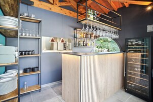 Uma área de bar com prateleiras de copos, garrafas e um climatizador de vinhos.