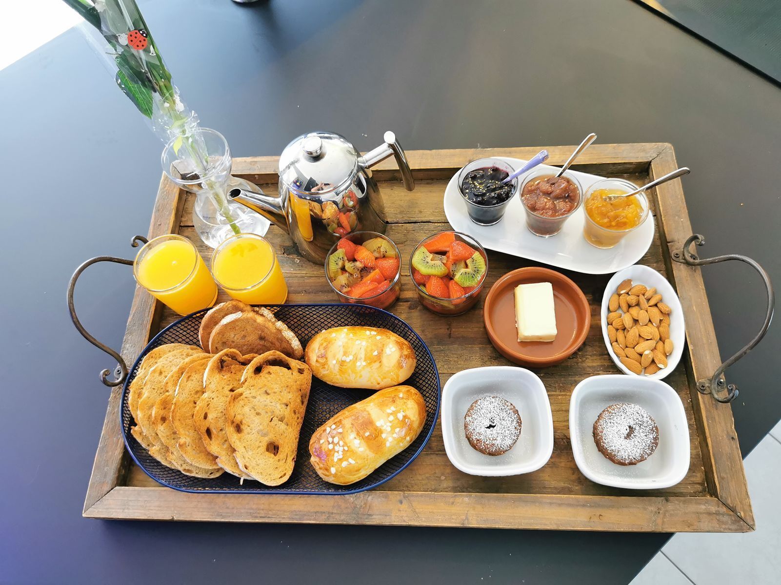 A breakfast tray with bread, pastries, fruits, and beverages.