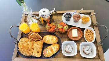 A breakfast tray with bread, pastries, fruits, and beverages.