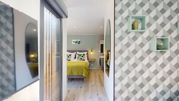 Quarto moderno com cama, mesa de cabeceira e parede com padrões geométricos.