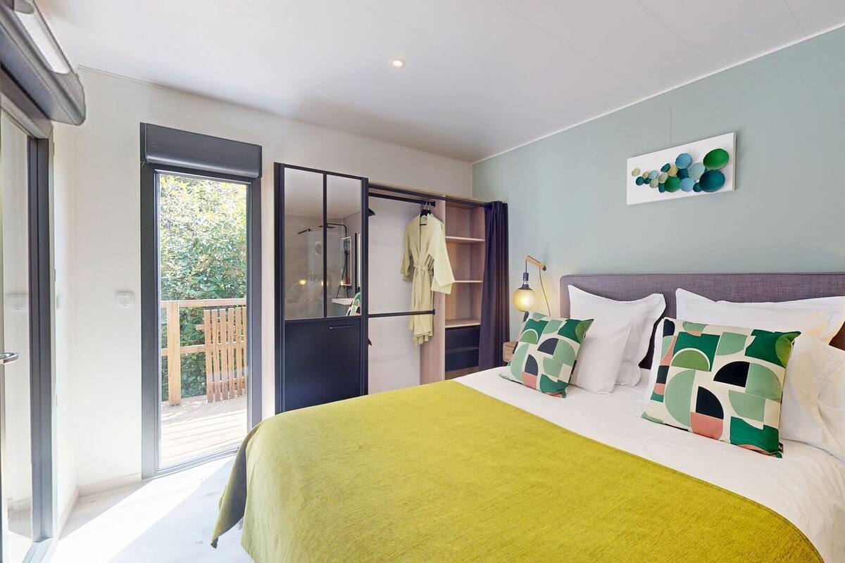 Une chambre à coucher avec un lit, une fenêtre, une porte et une vue sur la verdure à l’extérieur.