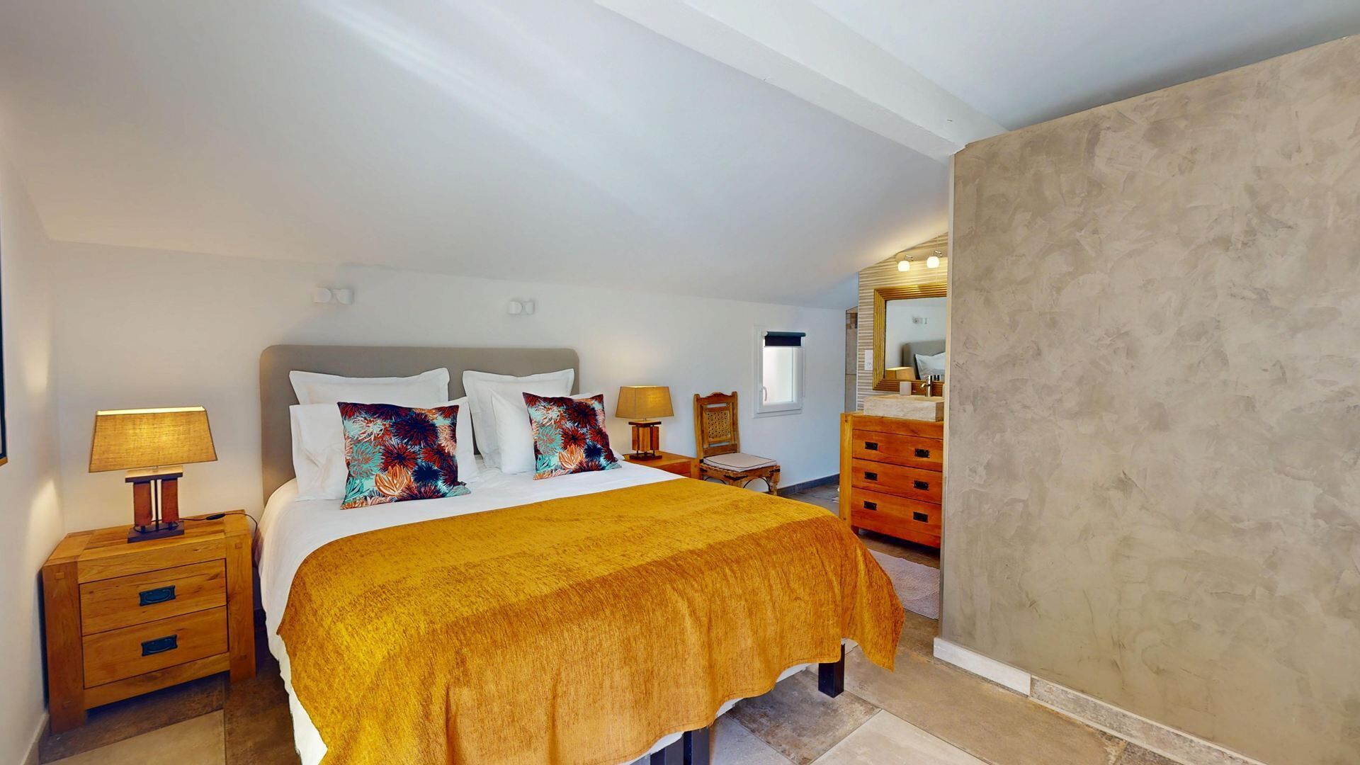 A bedroom with a bed, nightstands, a dresser, and a large mirror.