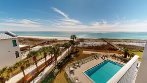Una propiedad frente a la playa con piscina, palmeras y vista al océano.