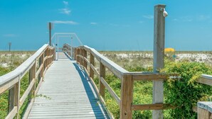 Un paseo marítimo de madera que lleva a una playa, bajo un cielo despejado.