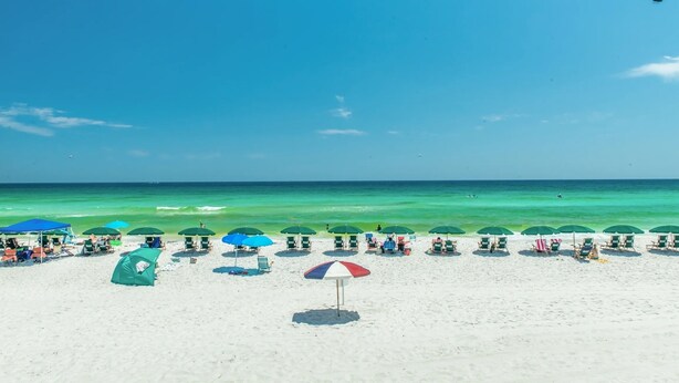 Una playa con hileras de sombrillas y sillas de playa.