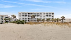Un hôtel en bord de mer doté de nombreux balcons et donnant sur une plage de sable.