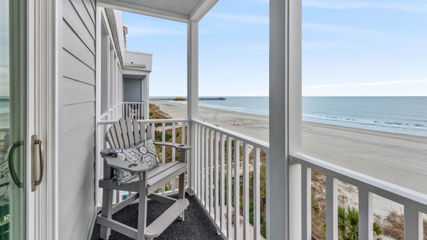Un balcon avec vue sur la plage et l’océan.