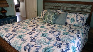 Une chambre à coucher avec une couvre-lit à motifs floraux, une tête de lit en bois et une table de chevet avec une lampe.