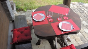 A wooden table set with red placemats, plates, and glasses, accompanied by red cushions on benches. - Lovingly furnished Alphüttli (Wilderswil)