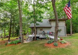 A cabin with a porch, steps, and an American flag.