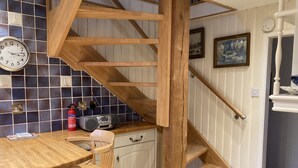 Une cuisine avec un escalier en bois, une horloge et une radio.