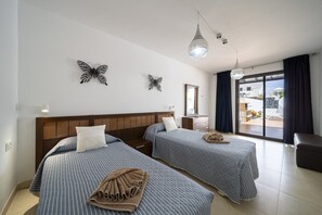 Hotellihuone, jossa on kaksi sänkyä, suuri ikkuna, parveke ja koristeellinen perhosaiheinen seinätaideteos.