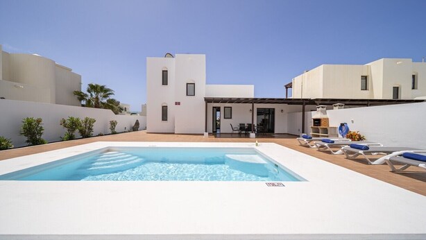 Ein modernes Gebäude mit Swimmingpool und Liegestühlen.