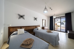A hotel room with two beds, a large window, a balcony, and decorative butterfly wall art.