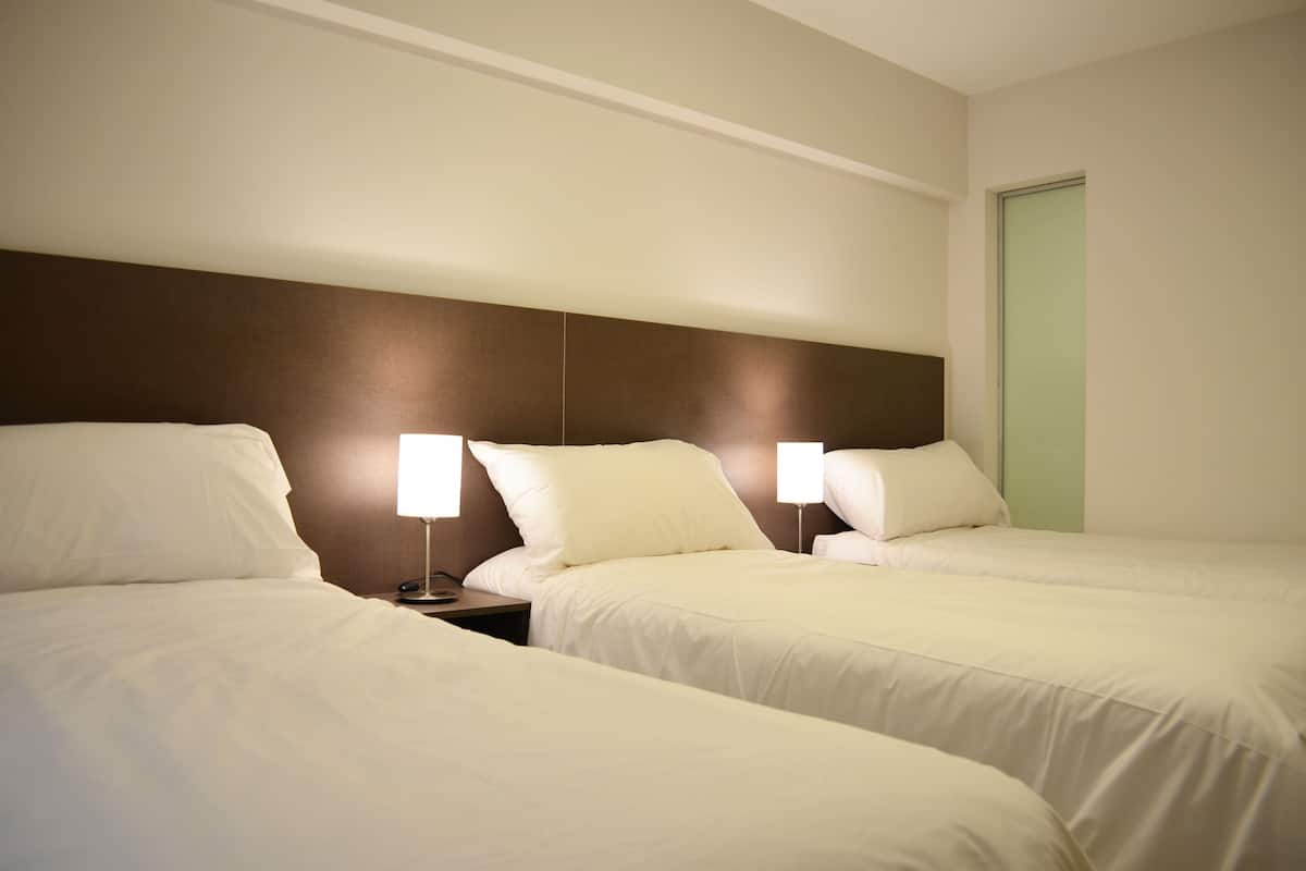 Une chambre d’hôtel avec deux lits simples, chacun étant équipé d’une table de chevet et d’une lampe.