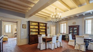A dining area with a wooden table and chairs, a chandelier, and a large bookcase. - Villa / Independent home in Lucca with 9 bedrooms sleeps 18 (Lucca)