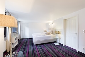 Relax in a spacious room with a large bed, bedside table, and TV on a stand.