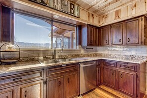 A kitchen with wooden cabinets, granite countertops, a stainless steel sink, and a dishwasher.