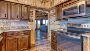Una cocina con armarios de madera, un microondas de acero inoxidable y un horno.